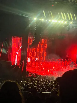 Red lights on stage at Fiddler's Green Amphitheatre at night with the words Haim I Quit