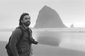 Man on the beach in front of a rock formation