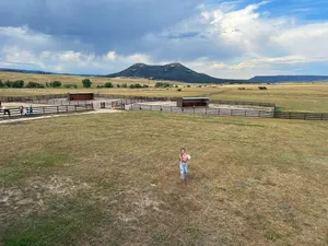 Theresa and the baby seen from a distance above, walking through a field on a farm