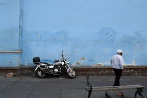 Motorcycle and man in white in front of a light blue wall