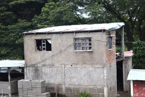 A woman looking out the window of a concrete building seen from the road