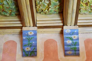 Ceiling detail of wood carved to look like leaves and some daisy paintings