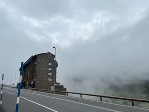 Tall stone building on the highway over a cliff in the fog