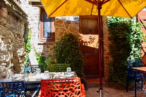 Outdoor cafe with colorful chairs under a yellow umbrella