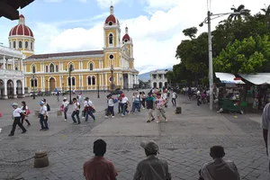 Line of schoolchildren crossing a plaza with a yellow colonial building