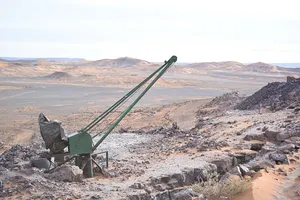 A green piece of abandoned metallic machinery amidst a vast, empty desertscape