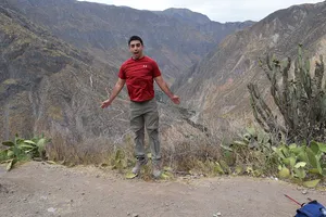 Andrew jumping with a silly expression in front of cacti and Colca Canyon