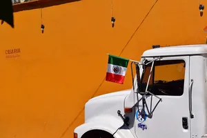 Truck flying Mexican flag in front of an orange wall
